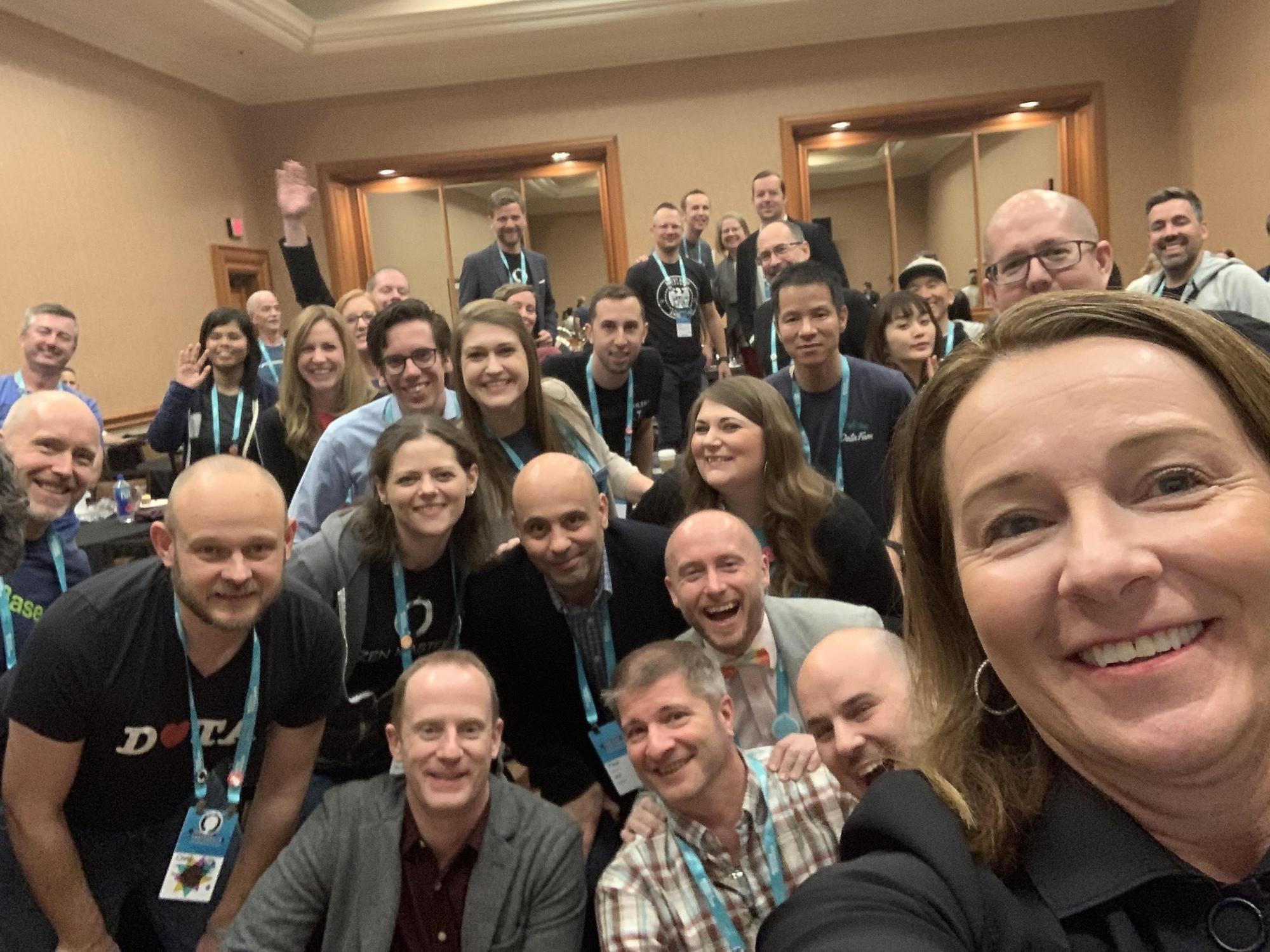 Large group of people with badges taking selfie at a conference